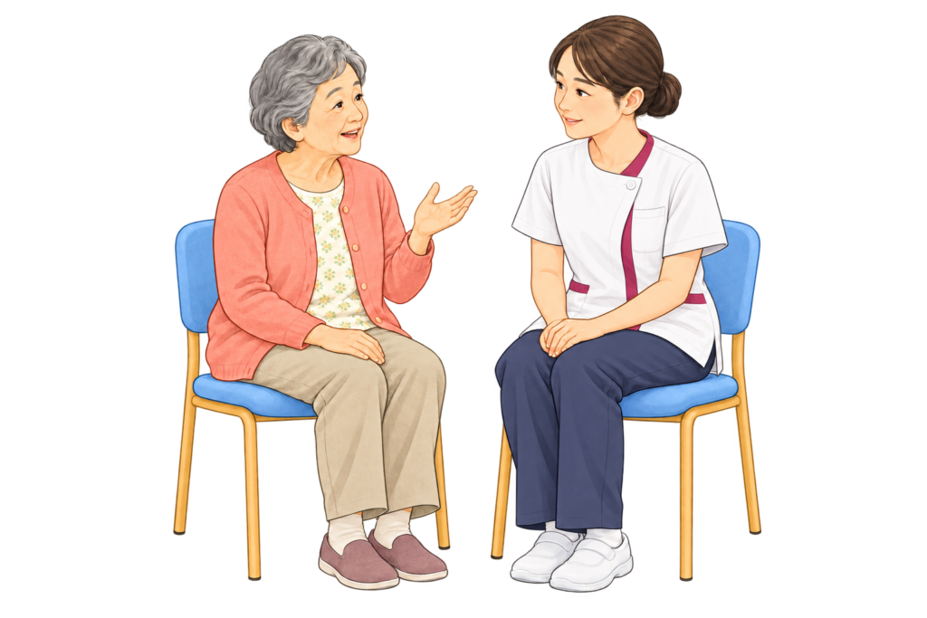 白とワインピンクの制服の看護師が、患者様と目線を合わせて話を聴くイラスト